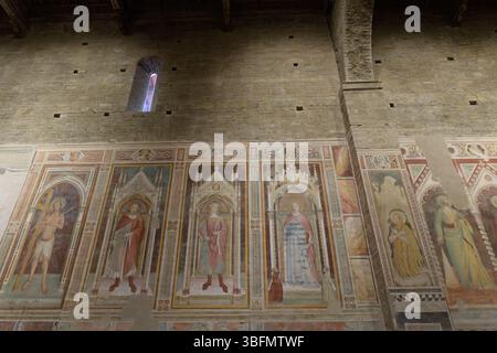 Fresken an der Kirchenwand von San Miniato al Monte, Florenz, Italien, mit Heiligen in gotischen architektonischen Rahmen aus dem 14. Jahrhundert. Stockfoto