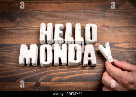 Hallo Montag. Betonbuchstaben und Kaffeetasse auf dunklem hölzernem Texturhintergrund. Stockfoto