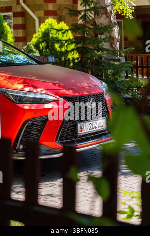 Bischkek, Kirgisistan - 12. Oktober 2024: Nahaufnahme des Kühlergrills und der Scheinwerfer eines roten Lexus NX350 SUV mit Grün im Hintergrund Stockfoto