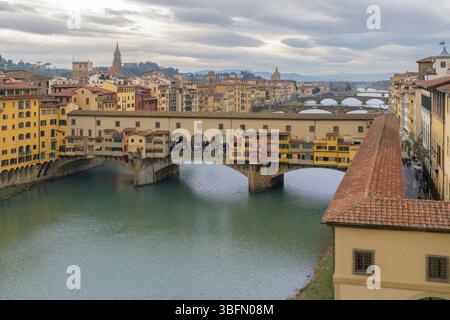 Panoramablick auf Ponte Vecchio über den Fluss Arno mit Vasari Korridor und farbenfrohen mittelalterlichen Gebäuden in Florenz, Italien. Stockfoto