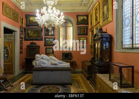 Innenraum des Stibbert-Museums in Florenz, Italien, mit einem Raum mit Möbeln aus dem 19. Jahrhundert, Gemälden und einer neoklassizistischen Grabskulptur aus Marmor Stockfoto