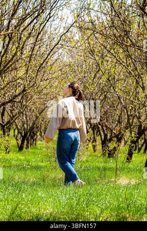 Bild von einem Mandelgarten, während ein sehr schönes und attraktives Mädchen im Busen der Natur spaziert und die Schönheit unseres Planeten bewundert. Das ist sie Stockfoto