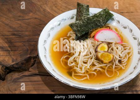 Es wird eine Schüssel Ramen serviert, mit Nudeln, Brühe, Algen, Eiern, und Kamaboko, das eine wohltuende und geschmackvolle Mahlzeit anbietet. Stockfoto