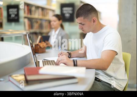 Der Student liest Bücher und arbeitet am Laptop Stockfoto