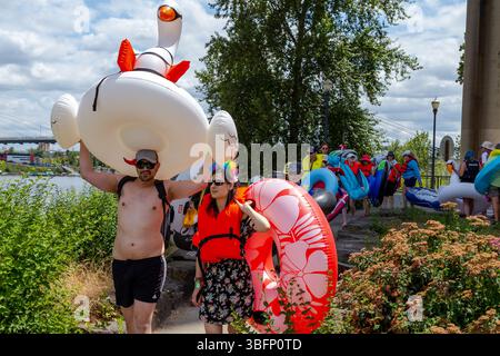 The Big Float, Portland, Oregon – 13. Juli 2019: Die Menschen tragen aufblasbare Schwäne und Röhren zum Willamette River, um einen lustigen Sommerwagen zu machen. Stockfoto