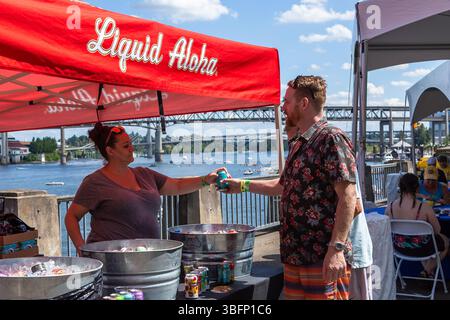 The Big Float, Portland, Oregon – 13. Juli 2019: Ein Anbieter überreicht einem Kunden eine Dose Liquid Aloha bei einer Veranstaltung im Freien mit Flussblick. Stockfoto