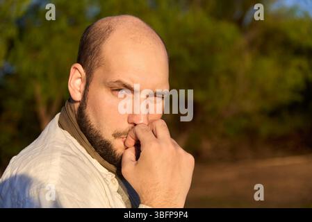 Hispanischer Reisender, der bei Sonnenaufgang am Ufer eines Baches sitzt und die ersten Sonnenstrahlen empfängt, während er gerne einen Keks isst. El Palmar National Stockfoto