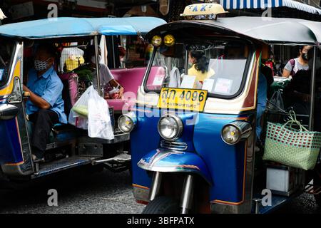 Zwei Tuk Tuks, die an einem geschäftigen Morgen im Soi 20, einem Straßenmarkt in einem multikulturellen Viertel Bangkoks, im Verkehr stecken geblieben sind und Passagiere mit Lebensmitteln befördern Stockfoto
