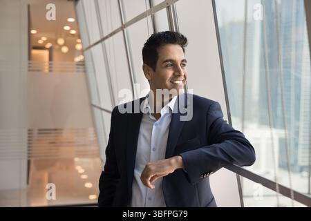 Geschäftsmann in elegantem dunklen Anzug mit Blick aus dem Panoramafenster Stockfoto