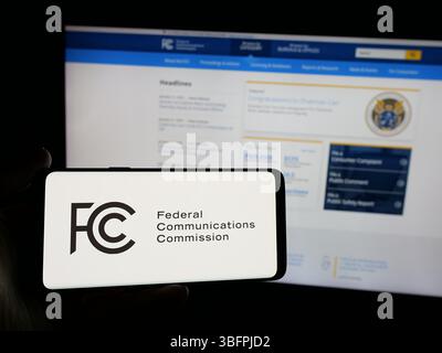 Stuttgart, Deutschland - 23. 01. 2025: Person mit Smartphone mit Logo der US-Behörde Federal Communications Commission (FCC) auf dem Bildschirm Stockfoto
