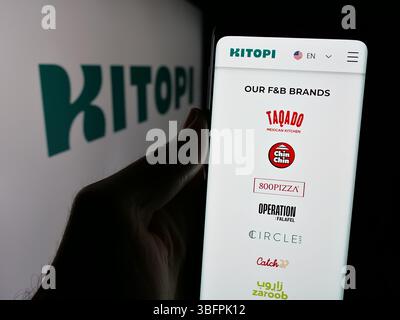 Stuttgart, Deutschland - 23.01.2025: Person, die ein Handy hält, mit Webseite des arabischen Gastronomieunternehmens Kitopi vor dem Logo. Stockfoto