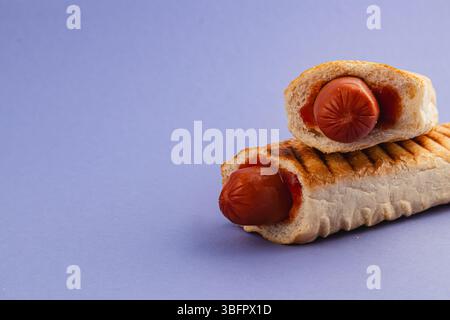 Juicy grilled hot dogs nestled in toasted bread, served on a vibrant purple background. Perfect for a summer barbecue or casual meal. Stockfoto