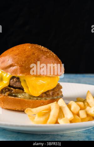 Zerschmettern Sie Burger mit Cheddar-Käse und karamelisierten Zwiebeln, serviert mit Pommes frites Stockfoto