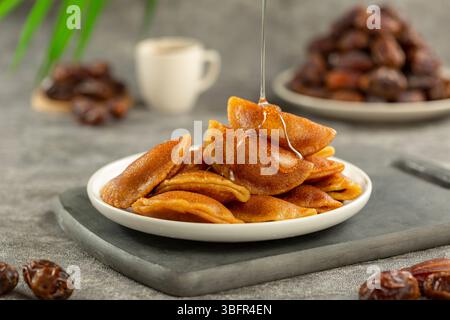 Qatayef wurde mit Zuckersirup getränkt, Nahaufnahme mit knuspriger gebratener Textur, die während des Ramadan abends warm serviert wurde Stockfoto