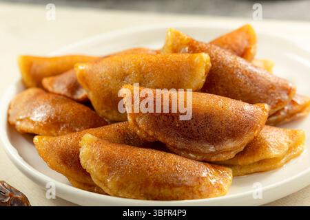 Makroaufnahme mit knusprigem, frittiertem Qatayef, gefüllt mit Nüssen und eingeweicht in Sirup, serviert während der Ramadan-Feierlichkeiten Stockfoto