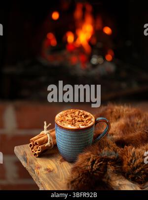 Sahlab Drink serviert in einer gemütlichen Winterszene mit Kamin, gekrönt mit Zimt und Zucker, klassisches arabisches Getränk Stockfoto