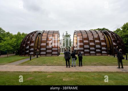 London, Großbritannien. Juni 2025. Der Serpentine Pavilion 2025, Eine Kapsel in Time, entworfen von der bangladeschischen Architektin und Pädagogin Marina Tabassum und ihrer Firma Marina Tabassum Architects (MTA), wird am 6. Juni 2025 eröffnet. Goldman Sachs unterstützt das jährliche Projekt zum 11. Jahr in Folge. Aus Holz gefertigt und um einen halbReifen Ginkgo-Baum gebaut (eine klimaresistente Baumart, die aus dem frühen Jura stammt) und eine Hälfte des Pavillons kann sich bewegen, um eine neue Konfiguration zu schaffen. Quelle: Mary-Lu Bakker/Alamy Live News Stockfoto