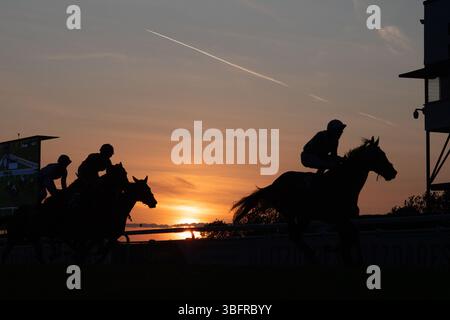 Windsor, Berkshire, Großbritannien. Juni 2025. Jockeys und Rennpferde stehen vor der Skyline, wenn die Sonne auf der Royal Windsor Racecourse in Windsor, Berkshire, während des letzten Rennens des Abends bei Monday Night Racing untergeht. Das Wetter wird sich diese Woche ändern, mit der Regenvorhersage für die nächsten Tage. Quelle: Maureen McLean/Alamy Live News Stockfoto