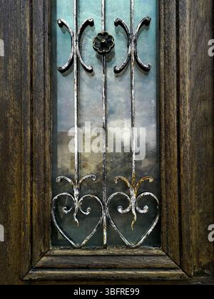 Durch diese Holztür mit wunderschönen Metalldesigns und farbenfrohen Glaspaneelen glänzt handwerkliches Können. Auvergne. Frankreich Stockfoto