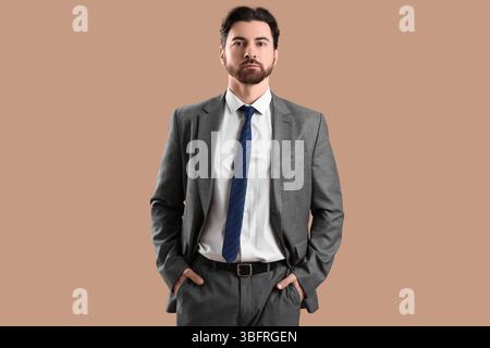 Hübscher junger Mann im Anzug auf beigefarbenem Hintergrund Stockfoto