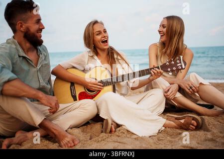 Eine Gruppe von Freunden, die gemeinsam Musik am wunderschönen Strand genießen Stockfoto
