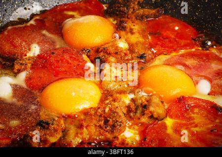 Spiegeleier mit Tomaten und Speck in heißem Fett Stockfoto