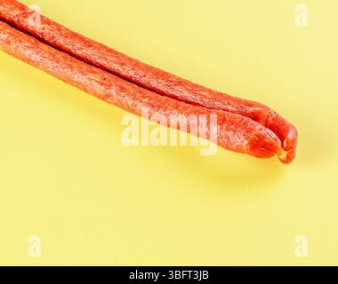 Dünner, getrockneter Wurststab auf hellgelbem Hintergrund Stockfoto