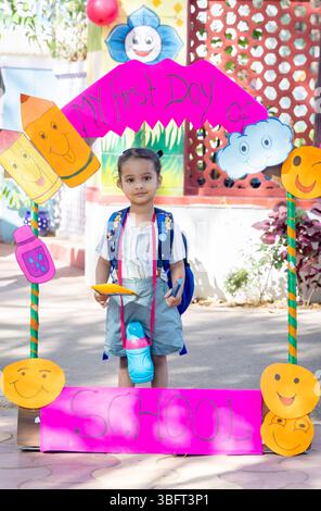 Entzückendes indisches Vorschulkind mit Fotostand am ersten Schultag im Freien Stockfoto