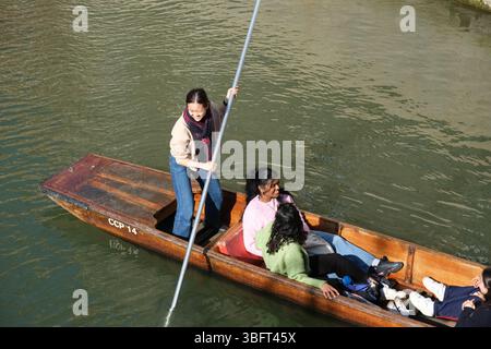 Eine junge Frau lächelt, als sie einen Punt auf dem Fluss Cam in der Nähe des Queens College in Cambridge manövriert Stockfoto