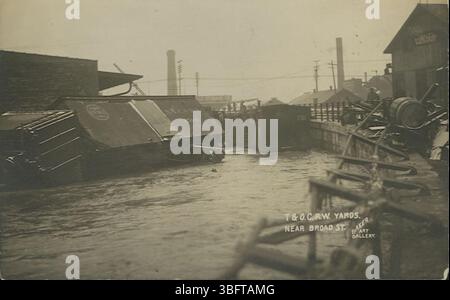 Diese schwarz-weiße Fotopostkarte von der Überschwemmung von 1913 in Columbus, Ohio, zeigt die umfangreichen Schäden an den Werften der Toledo und Ohio Central Railway in der Nähe der Broad Street. Das Bild zeigt die Zerstörung der Eisenbahninfrastruktur während des Hochwassers. Stockfoto