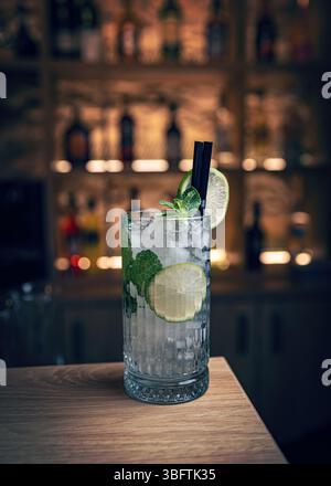 Erfrischender Mojito-Cocktail auf der Bartheke mit verschwommener hinterer Bar im Hintergrund Stockfoto