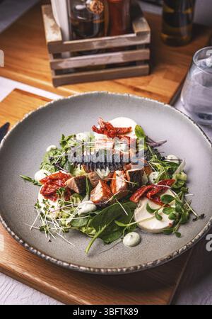 Lachssalat mit Mozzarella, sonnengetrockneten Tomaten und Mikrogrün werden am Restauranttisch serviert Stockfoto