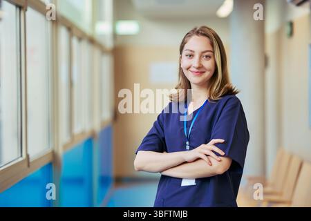 Junge selbstbewusste Krankenschwester lächelt im Krankenhausflur Stockfoto