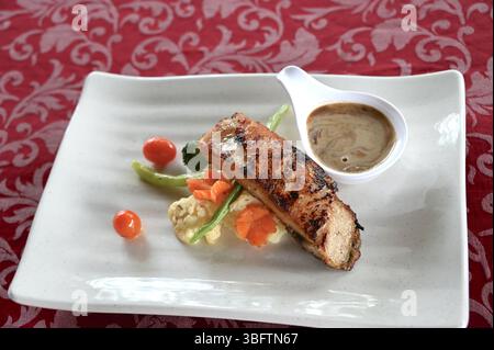 Gekochter Seebarsch, serviert mit Pilzsauce und Gemüse auf weißem Teller. Stockfoto