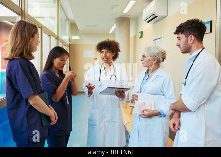 Medizinisches Team diskutiert Patientenstand im Krankenhauskorridor Stockfoto