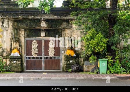 Bali, Indonesien - 10. Dezember 2024: Großes Gebäude mit grünem Mülleimer davor. Auf dem Gebäude befinden sich viele Statuen Stockfoto