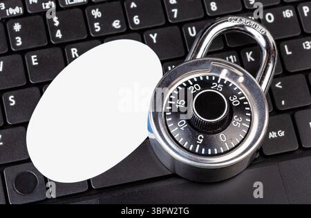 Ein einfaches Vorhängeschloss auf einer Laptop-Tastatur mit leerem, ovalem Logoausschnitt, Sicherheitskonzept für Cybersicherheit, verschlüsselter Zugriff Stockfoto