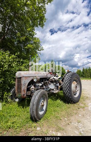 Ein alter rostiger Traktor, der unter einem Baum in Lutowiska, Polen, an einem schönen sonnigen Tag geparkt wurde Stockfoto