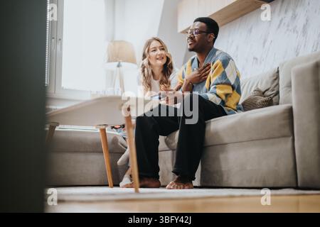 Ein vielseitiges Paar, das gemeinsame Freizeit in ihrem Wohnzimmer genießt Stockfoto