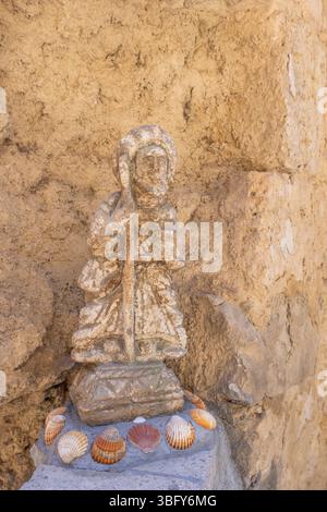 Verwitterte Statue des heiligen jakobus mit Stab, geschmückt mit Muscheln an der Basis, in Castrojeriz, Spanien, ein bedeutender Halt auf dem jakobsweg Stockfoto