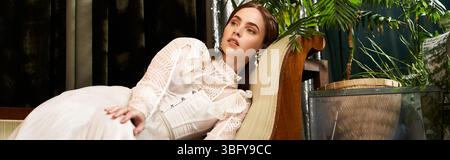 Eine anmutige junge Frau in einem Vintage-Kleid entspannt sich wunderbar im Grün, Banner Stockfoto