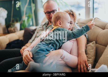 Die Familie genießt eine angenehme Zeit zu Hause, während sie auf einer gemütlichen Couch ihre Beziehung miteinander verbindet Stockfoto