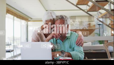 Bild: Fallende Ikonen über das kaukasische Seniorenpaar mit Laptop Stockfoto