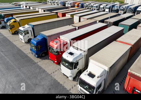 Aus der Vogelperspektive eines großen LKW-Parkplatzes an einem Logistikzentrum mit mehreren gewerblichen Sattelzügen, die in organisierten Reihen geparkt sind. Stockfoto