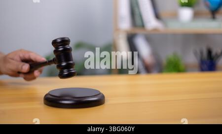 Eine Richterhand hält einen hölzernen Hammer, der Gerechtigkeit, Recht und Entscheidungsfindung symbolisiert. Das Bild zeigt Autorität, Gerichtsverfahren, Gerichtssaal-Einstellungen, per Stockfoto