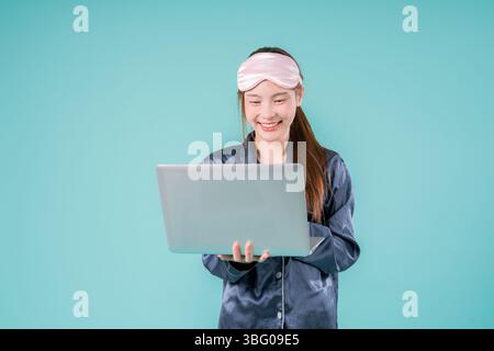 Asiatischer tragender Pyjama Unternehmer Notebook Social Lady, die online arbeitet, Eine junge Geschäftsfrau in Stockfoto