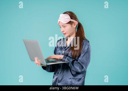 Asiatischer tragender Pyjama Unternehmer Notebook Social Lady, die online arbeitet, Eine junge Geschäftsfrau in Stockfoto