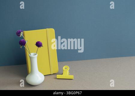 Notizbuch und Blumen auf dem Schreibtisch. marineblauer Wandhintergrund Stockfoto