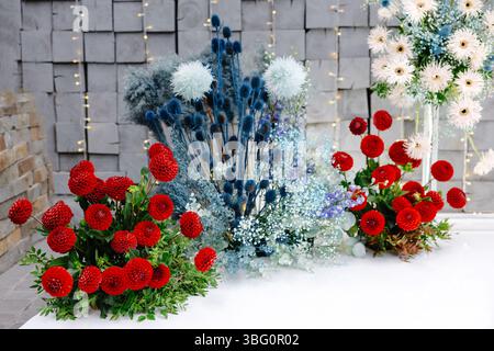 Blumenbogen mit hängenden Kronleuchtern, die eine graue Steinmauer beleuchten, schaffen eine romantische Atmosphäre für die Zeremonie Stockfoto