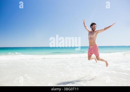 Männer, die im flachen Wasser springen, tragen rot-weiß gestreifte Badehosen, Kopierraum Stockfoto